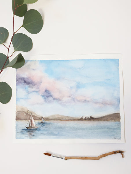 cotton candy skies with puffy clouds above a sailboat dotted lake watercolor landscape flat lay