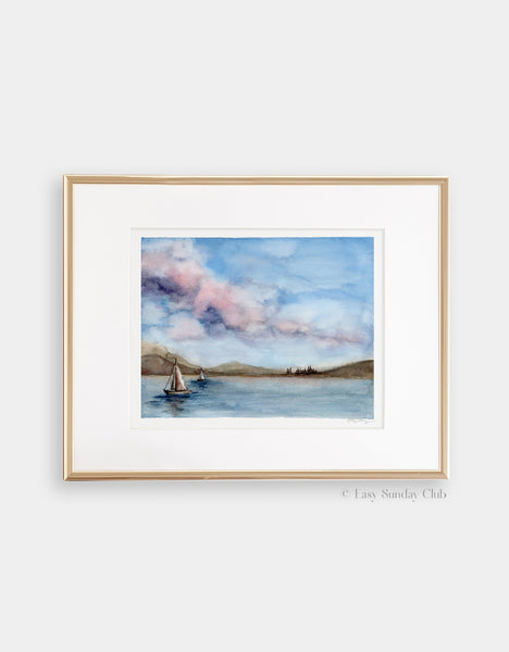 Gold framed mock up of cotton candy skies with puffy clouds above a sailboat dotted lake watercolor landscape