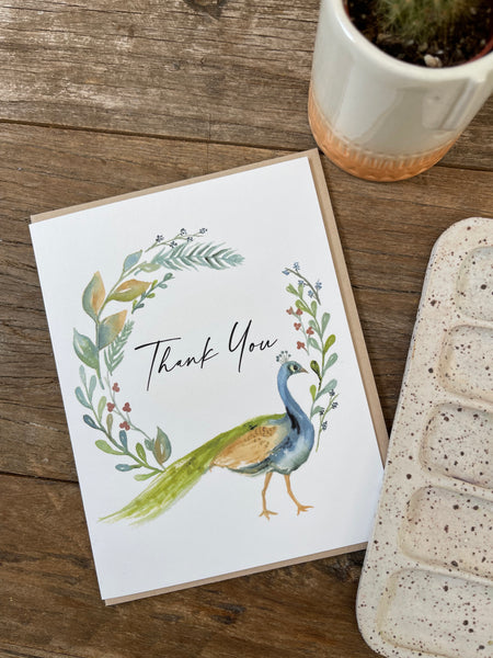 a thank you card with a watercolor peacock and fall themed wreath. The card is A2 size and blank inside.
