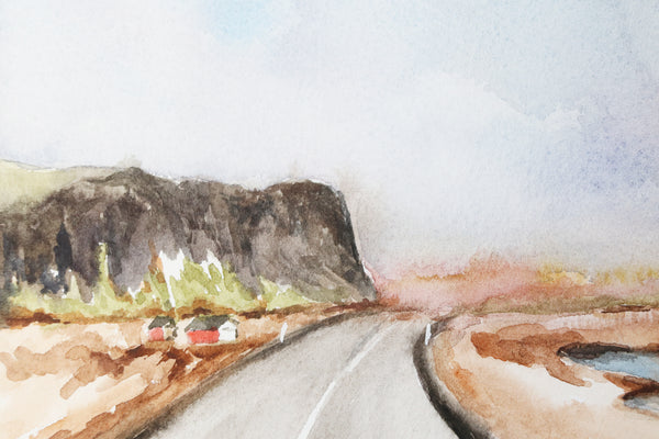 two red houses on the side of an open road with a large cliffside looming to the left close up